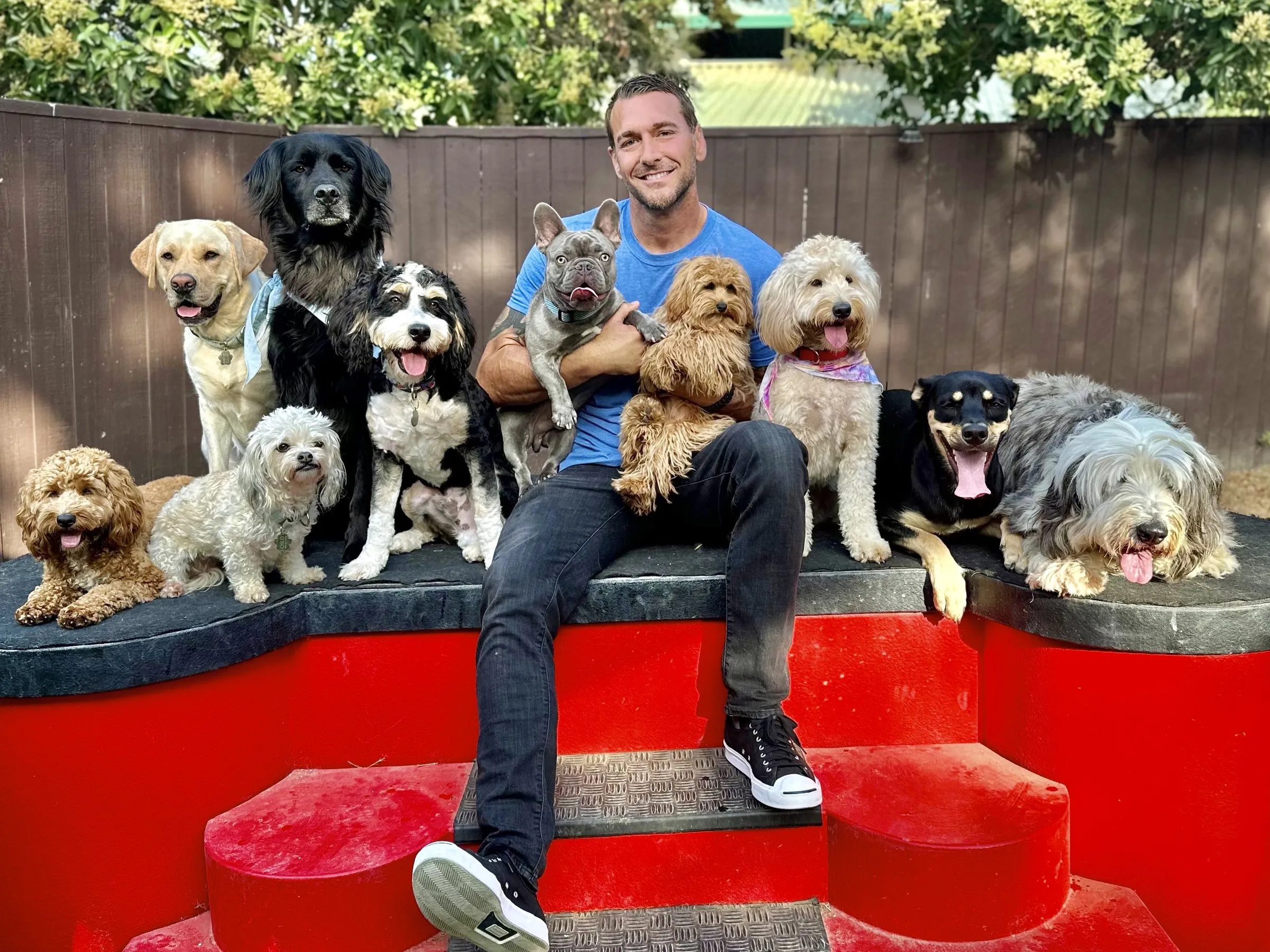 Brandon McMillan seated among a dozen dogs on the red bench at the ranch